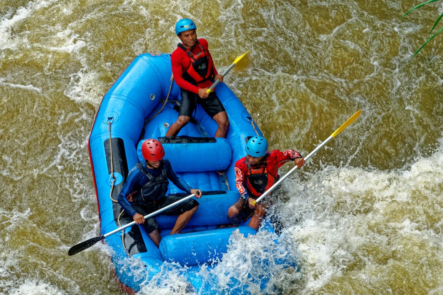 Exciting rafting adventure with a team navigating rapids in Cikidang, West Java. Enthusiastic paddlers in an inflatable blue raft.